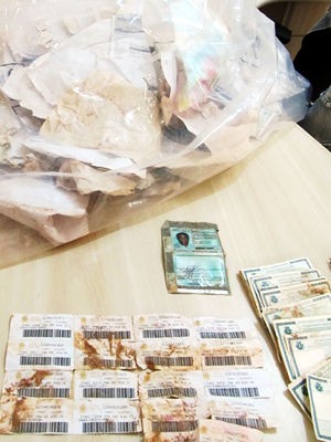 T&iacute;tulos de eleitor e RGs que foram serem encontrados em um c&oacute;rrego no bairro Capela do Pi&ccedil;arr&atilde;o, em V&aacute;rzea Grande - Foto: Divulga&ccedil;&atilde;o PRF