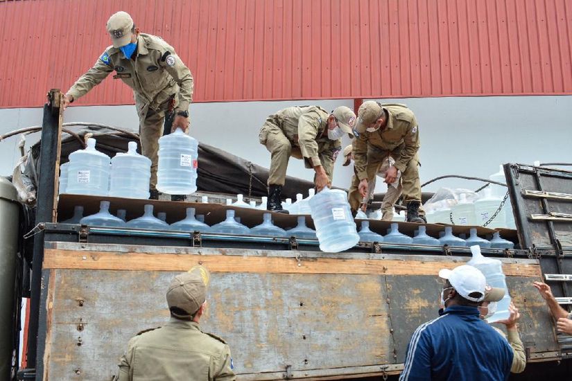 Bombeiros Militares descarregando galões de 20 litros de álcool. (Foto: Tchelo Fiigueiredo/Secom-MT)